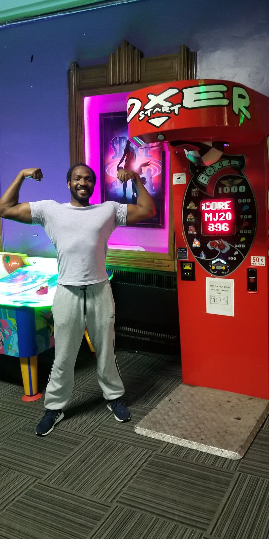 High score holder flexing beside the Boxer arcade machine
